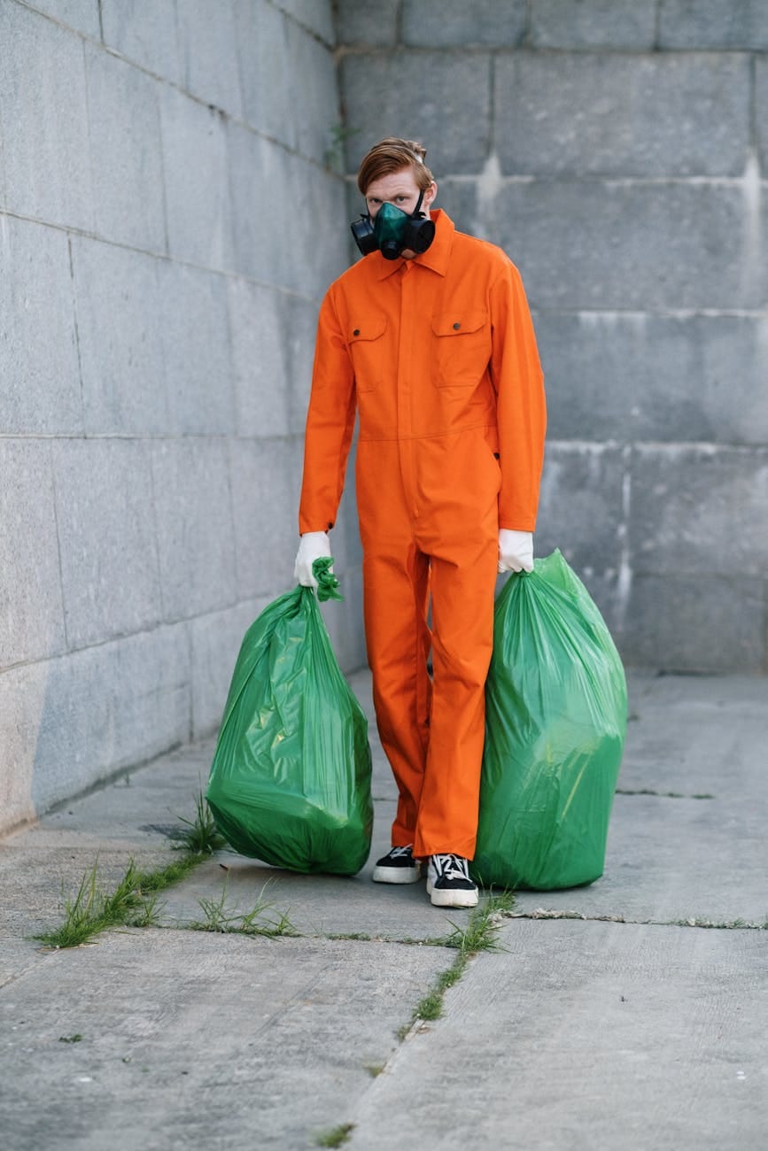 man wearing respirator holding green plastic bag